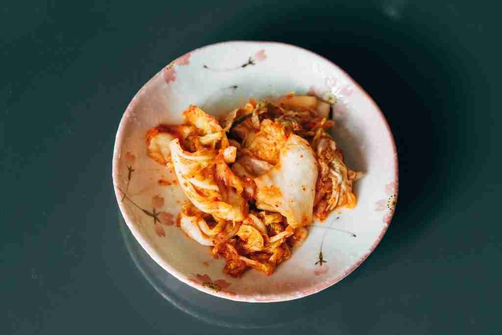 a white bowl of Kimchi on top of a table