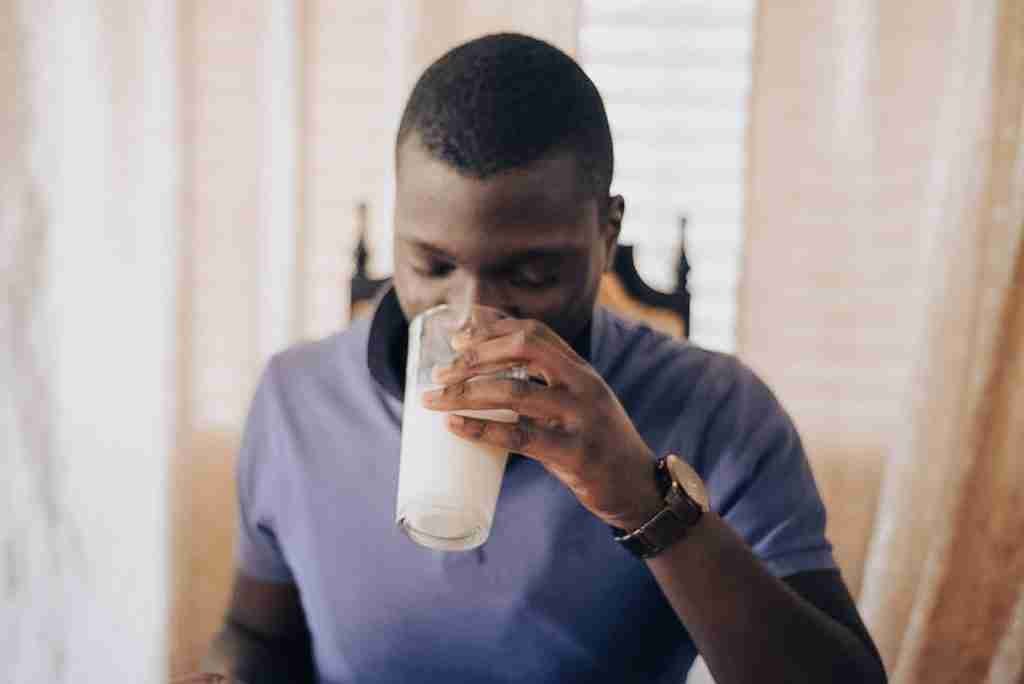 man in blue crew neck t-shirt drinking from glass