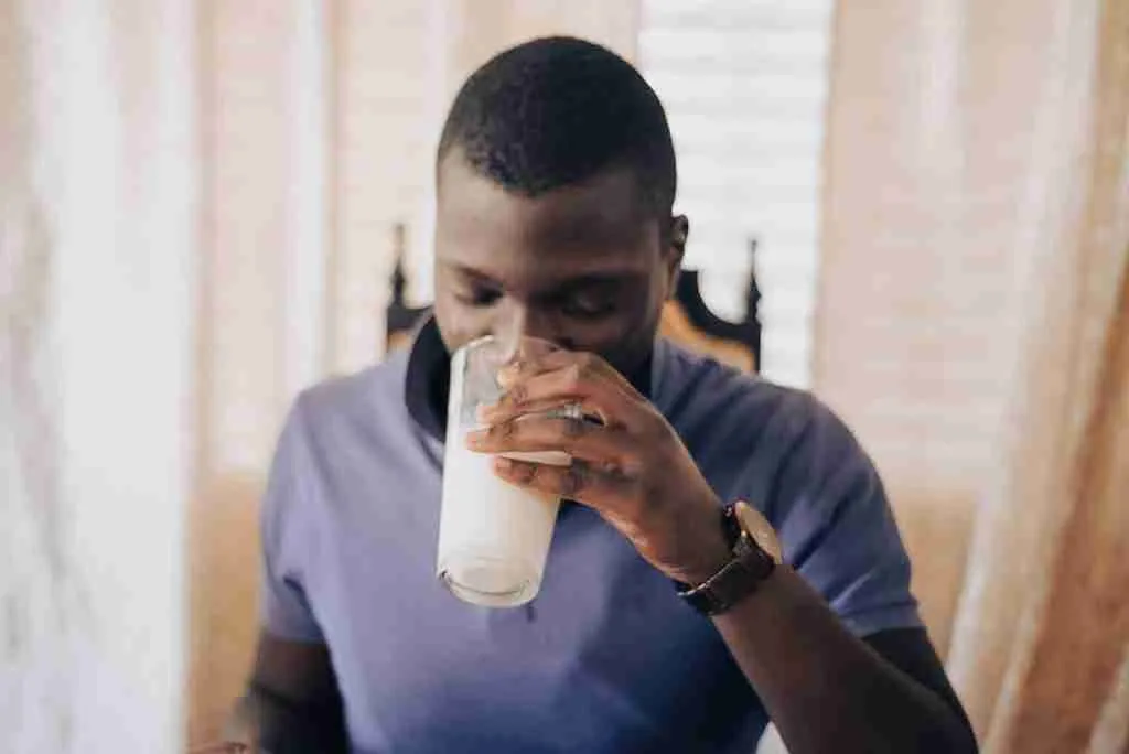 man in blue crew neck t-shirt drinking from glass