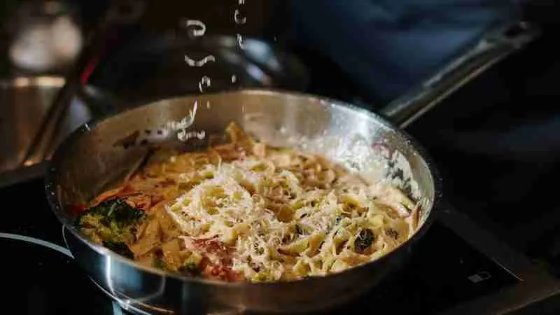 Person Holding Stainless Steel Cooking Pot With Pasta