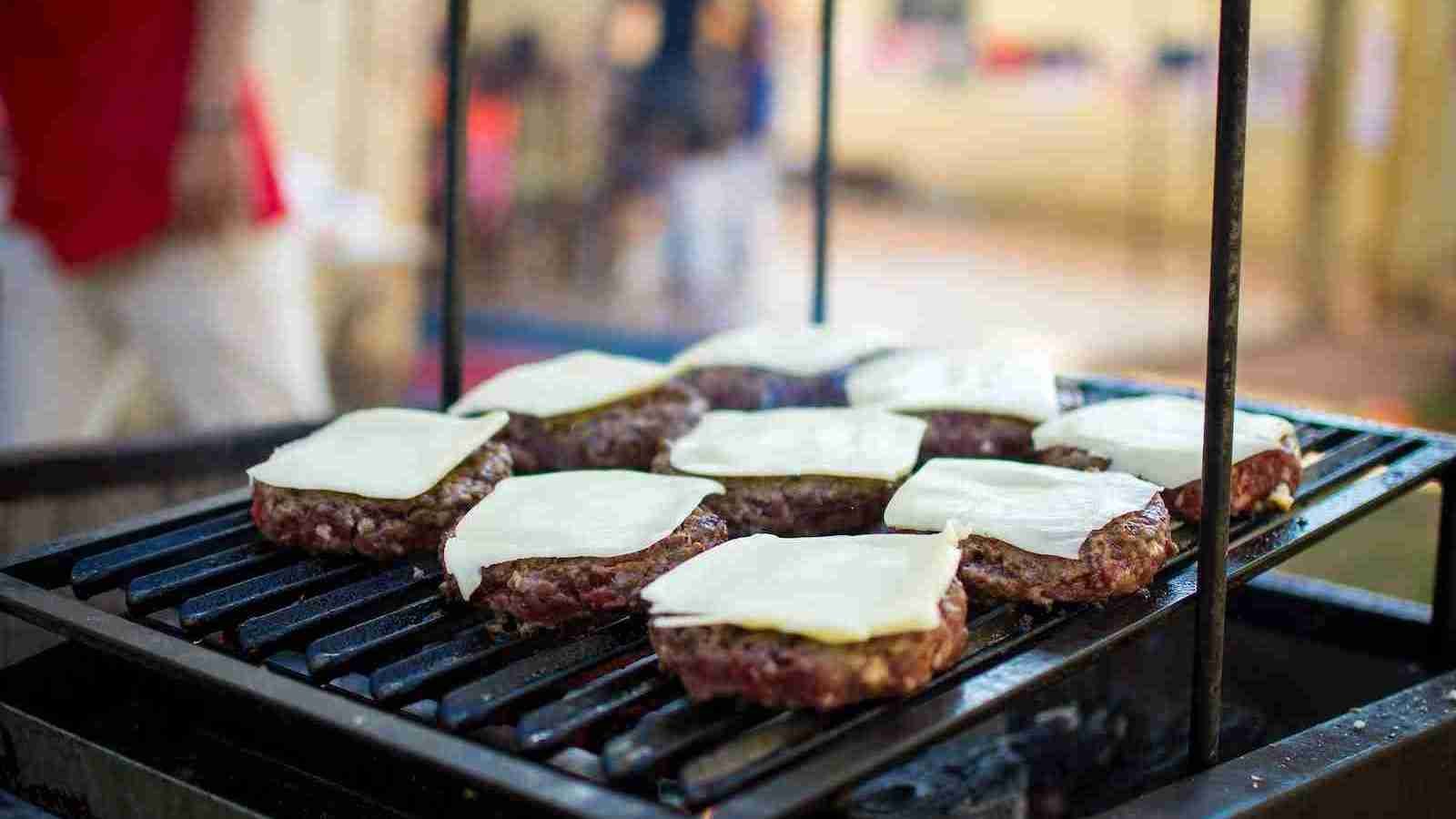 selective focus photography of meat patty with cheese on grill