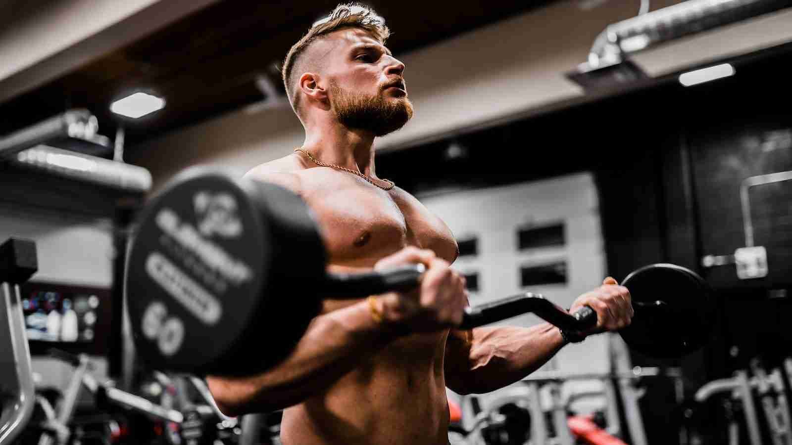 topless man in black shorts carrying black dumbbell