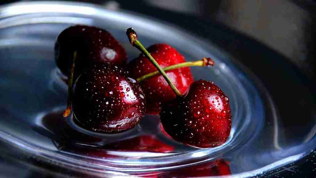three cherries in a bowl of water on a table