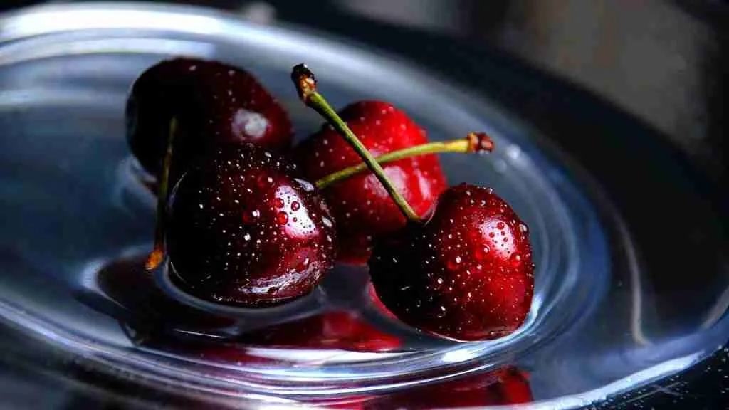 three cherries in a bowl of water on a table