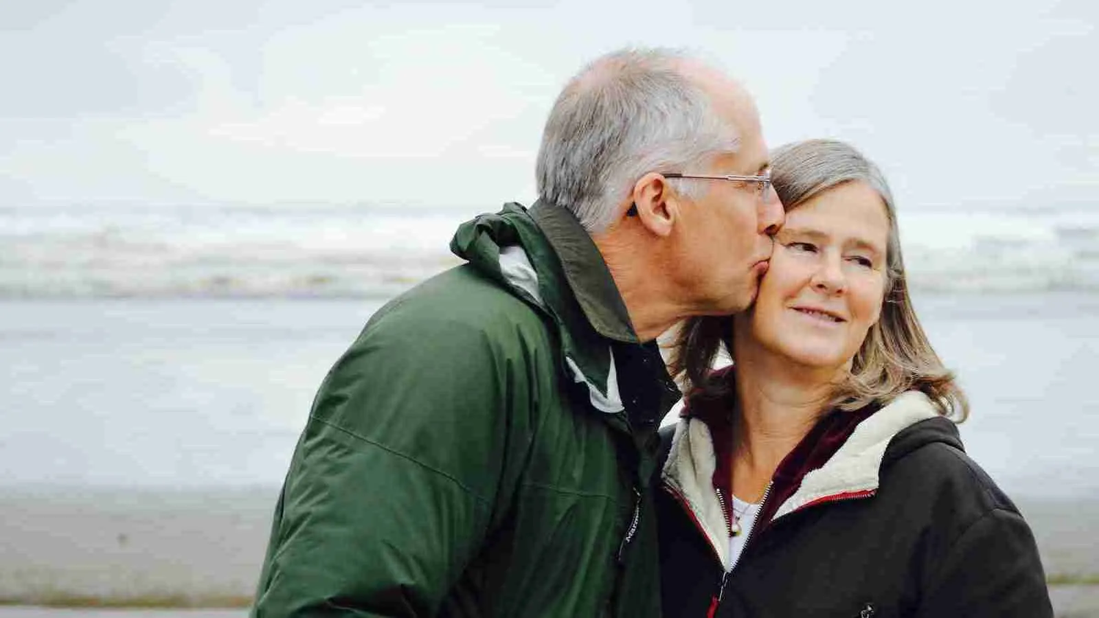 man kissing woman on check on a beach