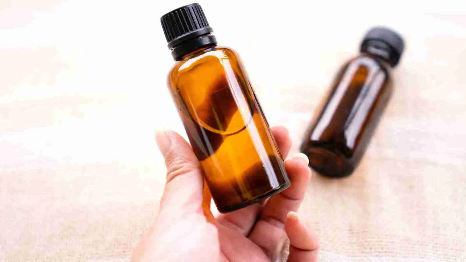 a person holding a bottle of essential oils