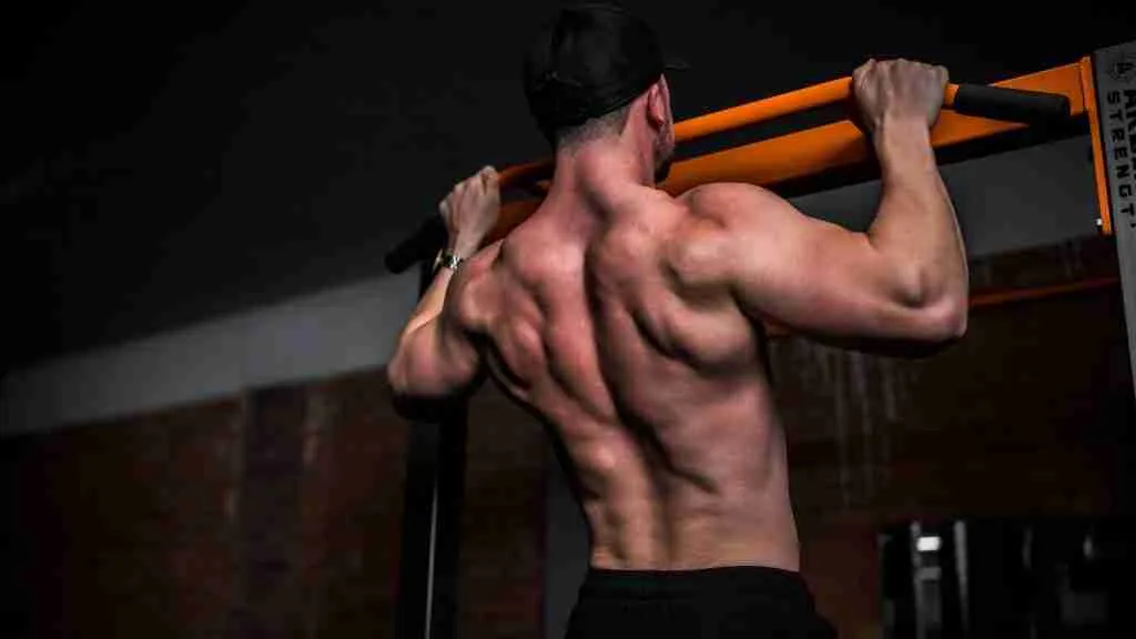 topless man in black shorts holding orange bar
