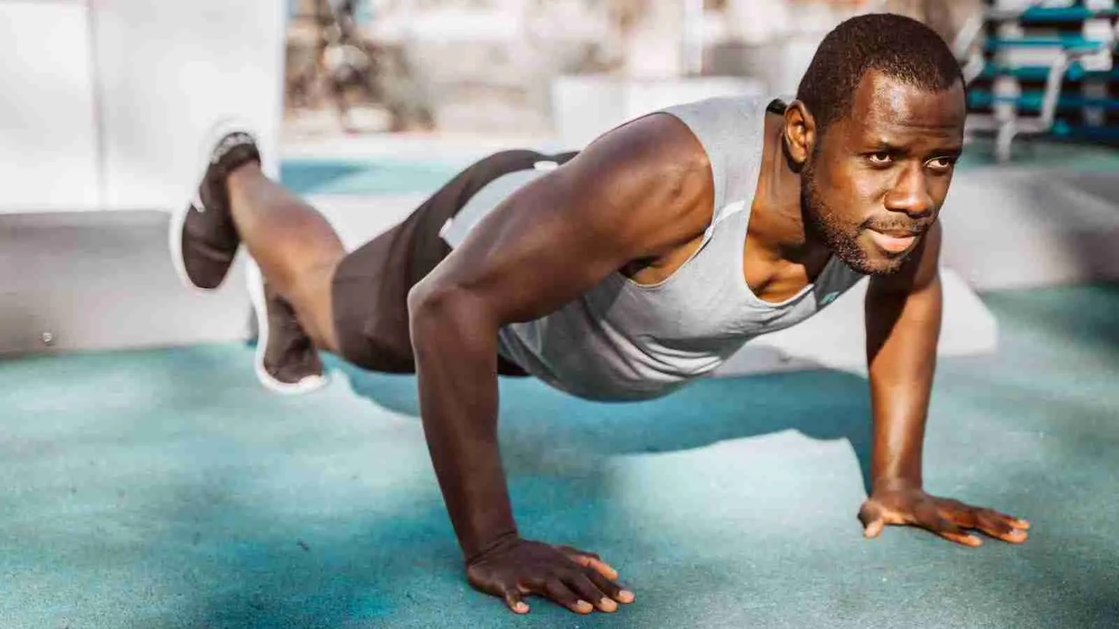 man in white tank top and gray shorts doing pushup