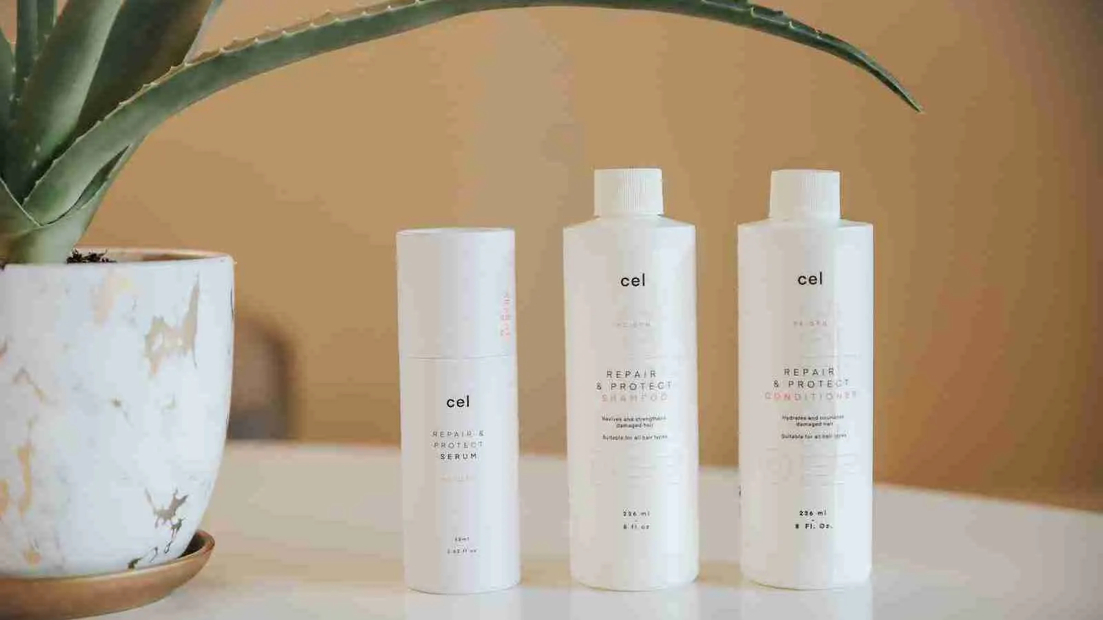 three bottles of vitamin C serum sitting on a table next to a potted plant