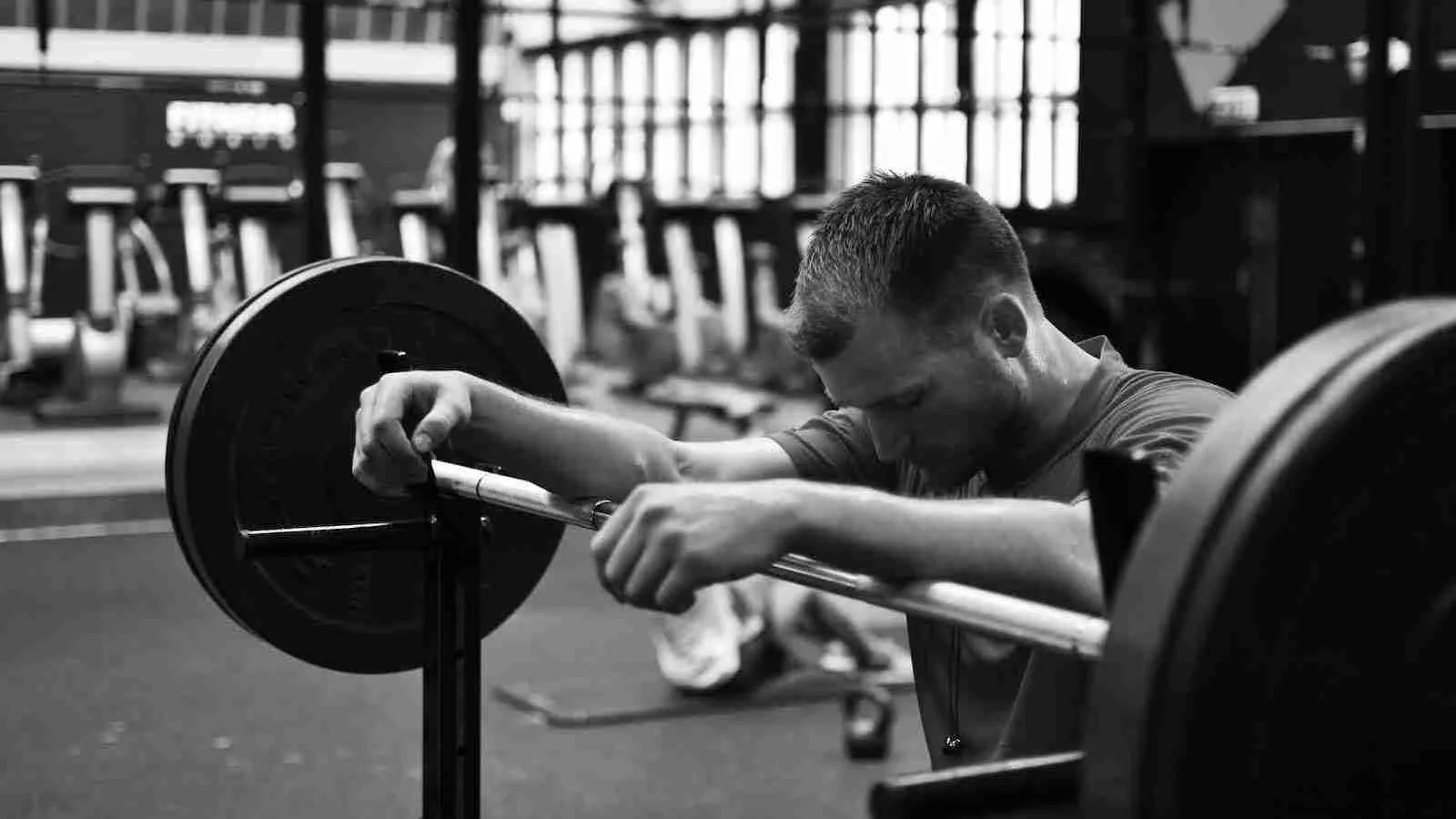 gray scale photo of man sitting on bench press