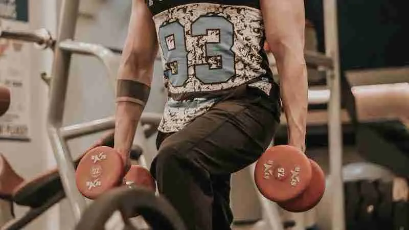 man in black and white tank top and brown shorts sitting on black and red exercise