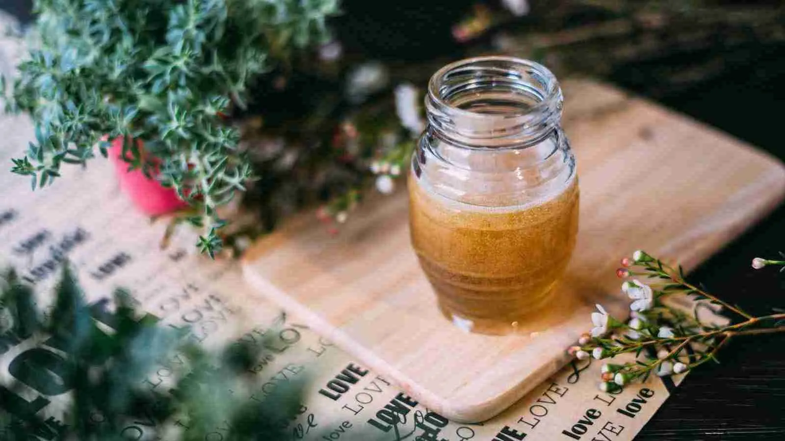 shallow focus photography clear honey jar on chopping board