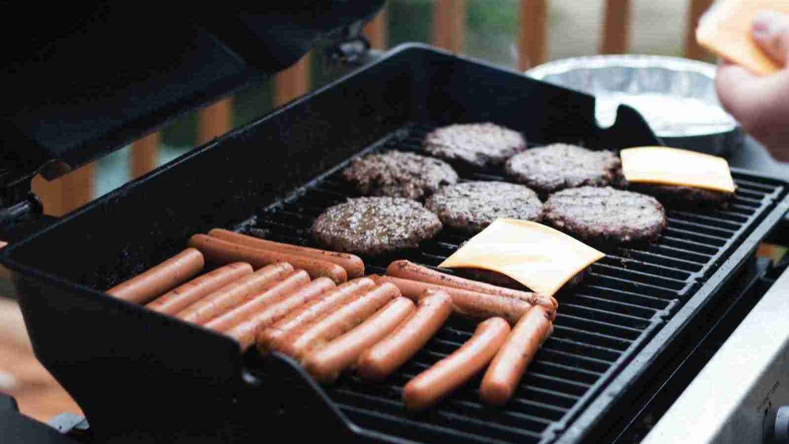 person standing in front grill grilling sausage