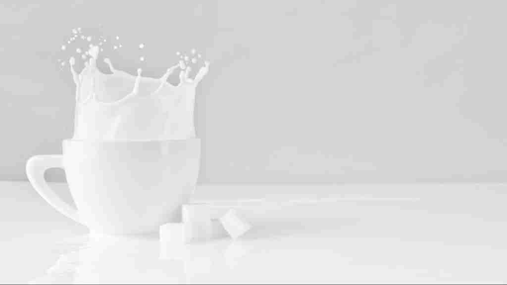 sugar block dropped on white cup with milk