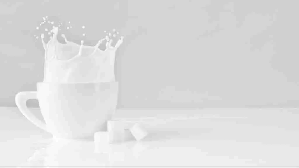 sugar block dropped on white cup with milk