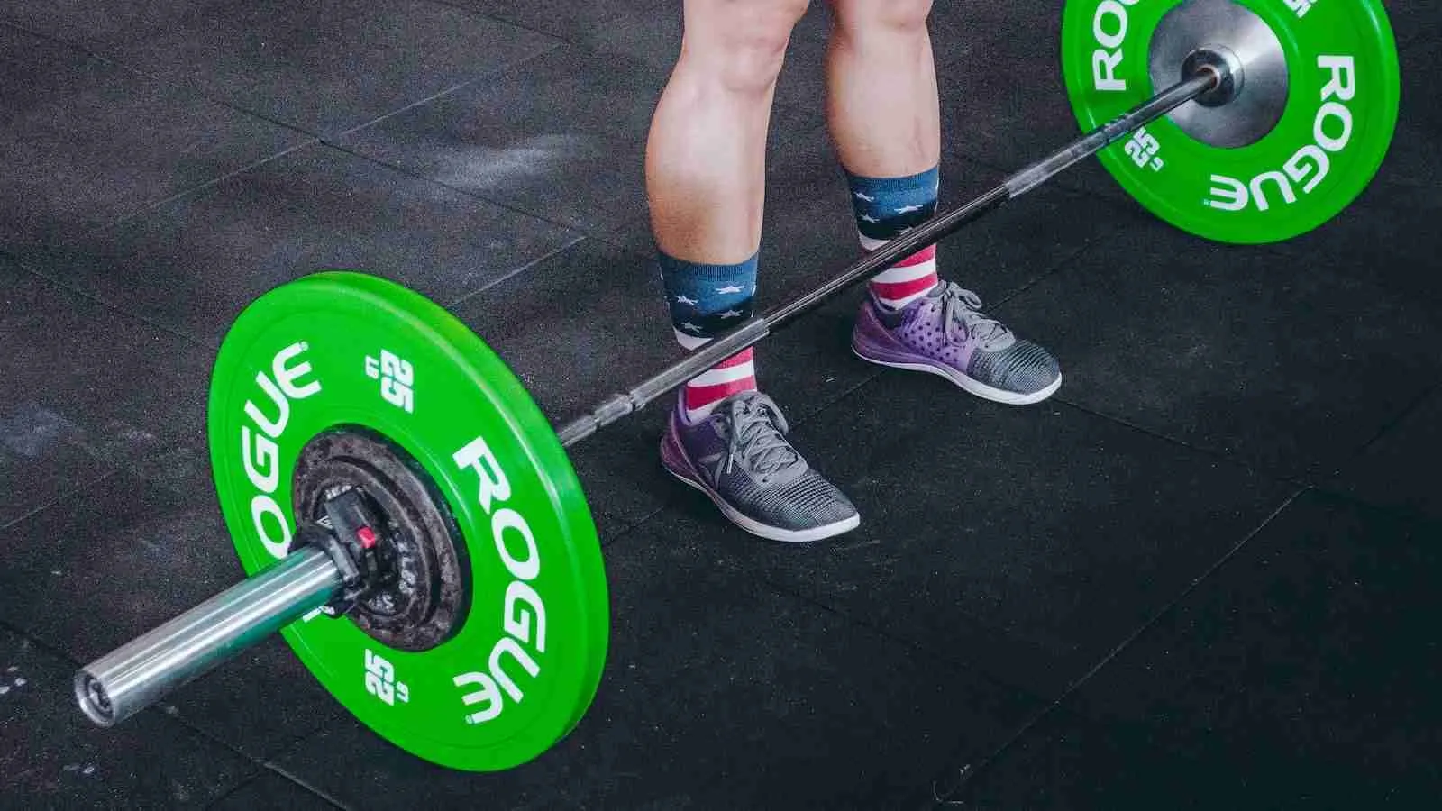 person standing in front of gray and green barbell