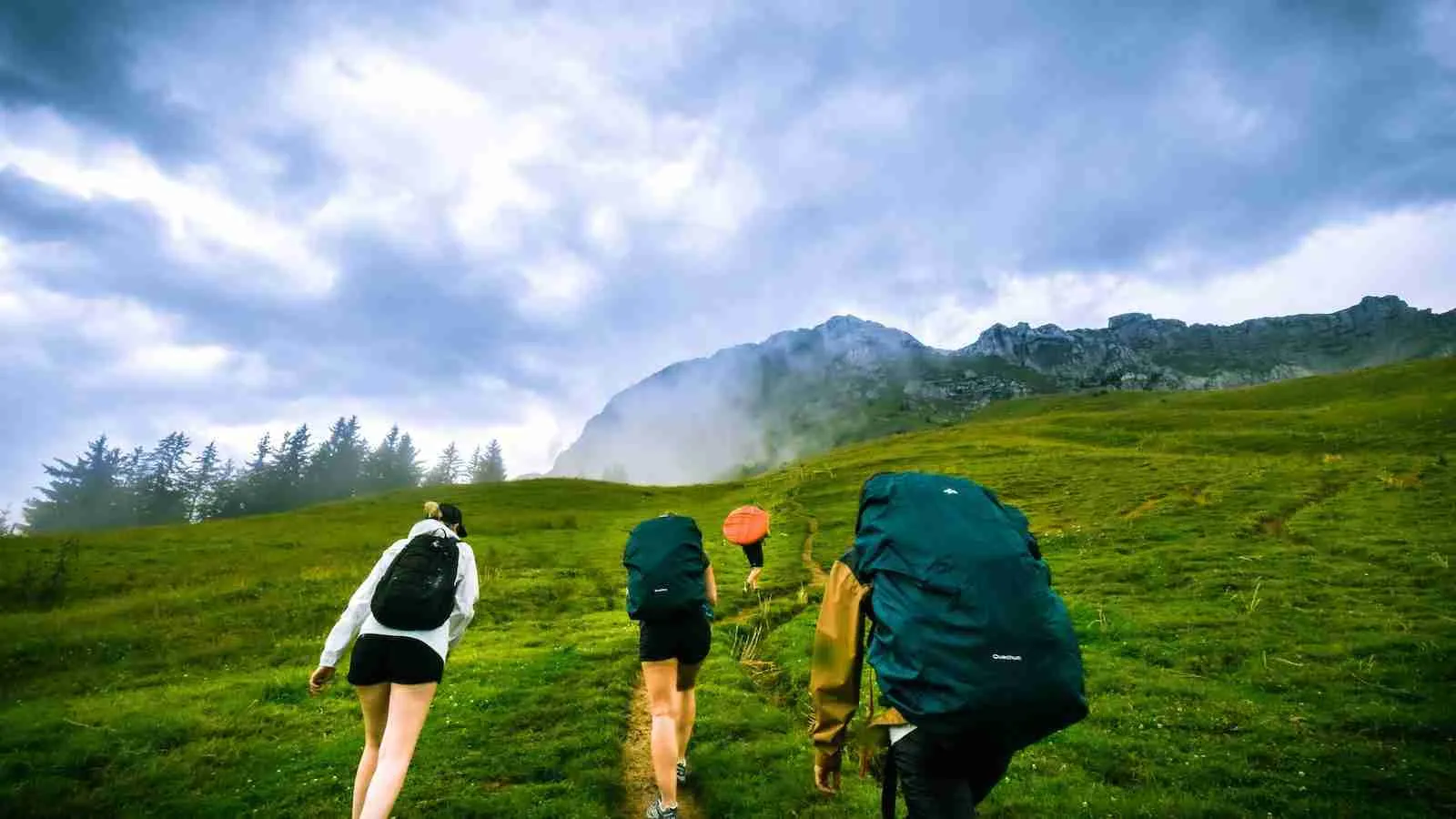 four person hiking on mountain hill during daytime