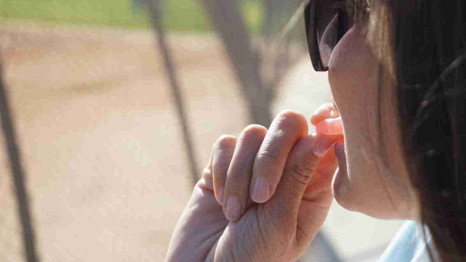 person wearing black framed sunglasses while eating a gummy 