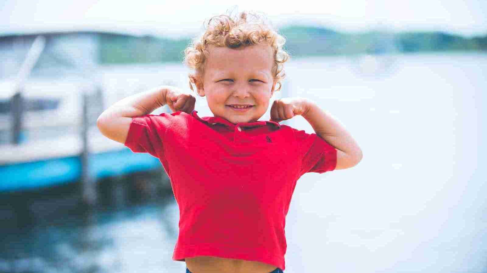 boy standing near dock flexing muscles