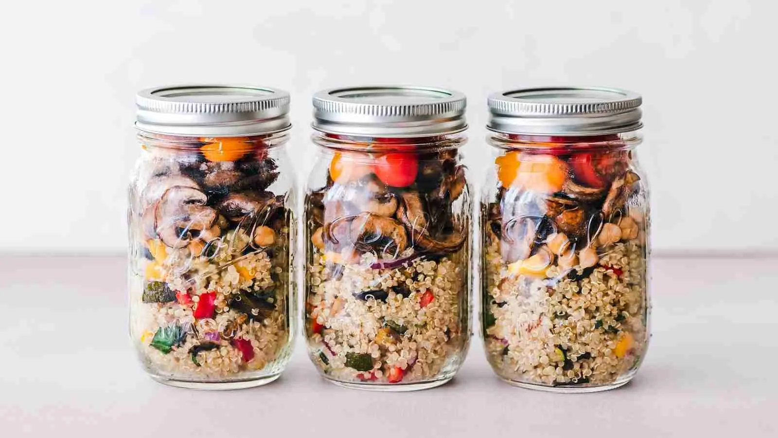 three full clear glass jars with with quinoa inside as well and other whole grains