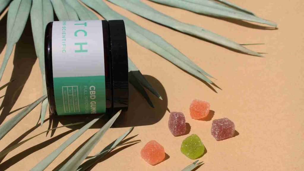 green and white labeled bottle with gummies place outside it