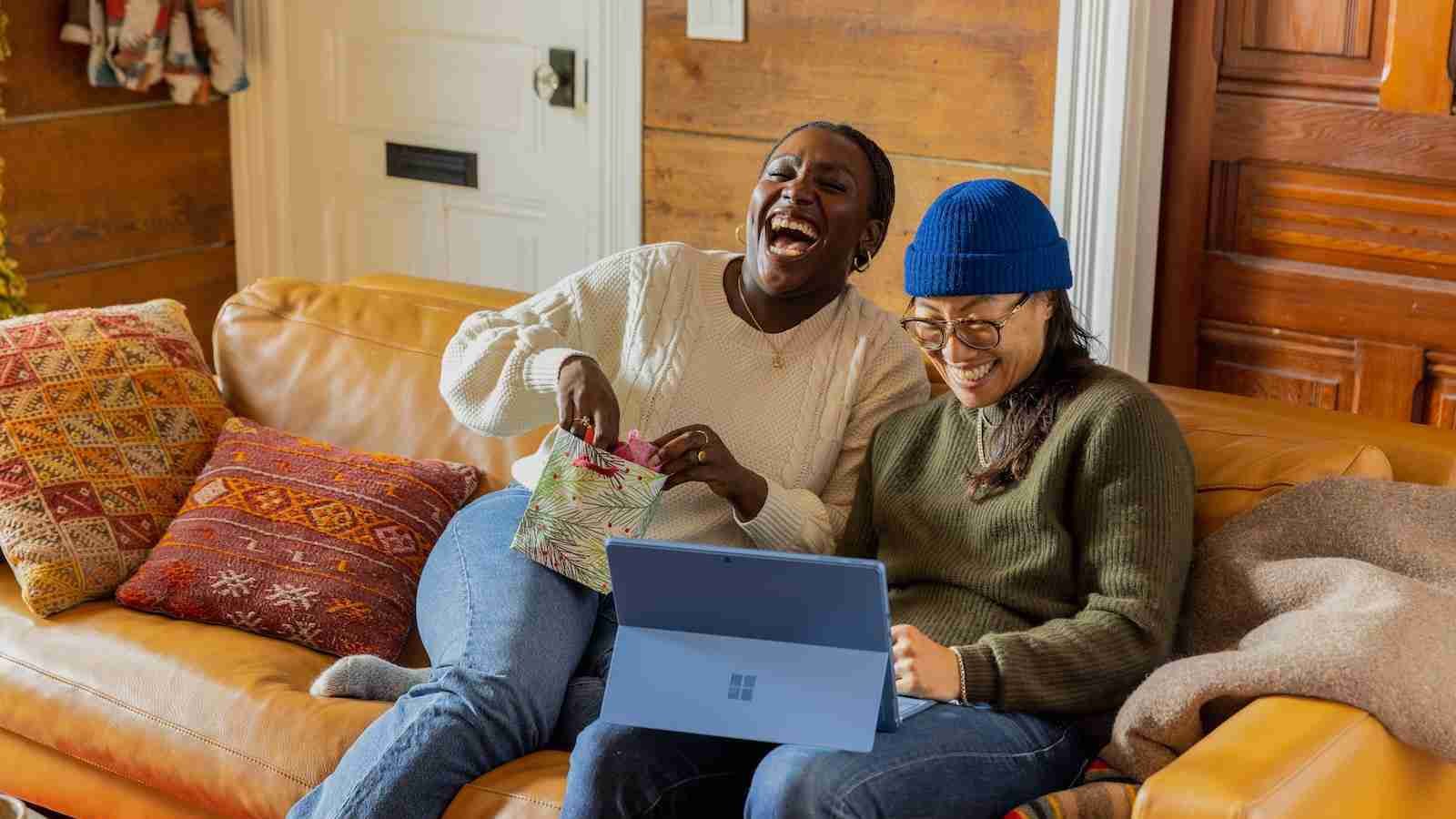 a person sitting on a couch with a laptop laughing.