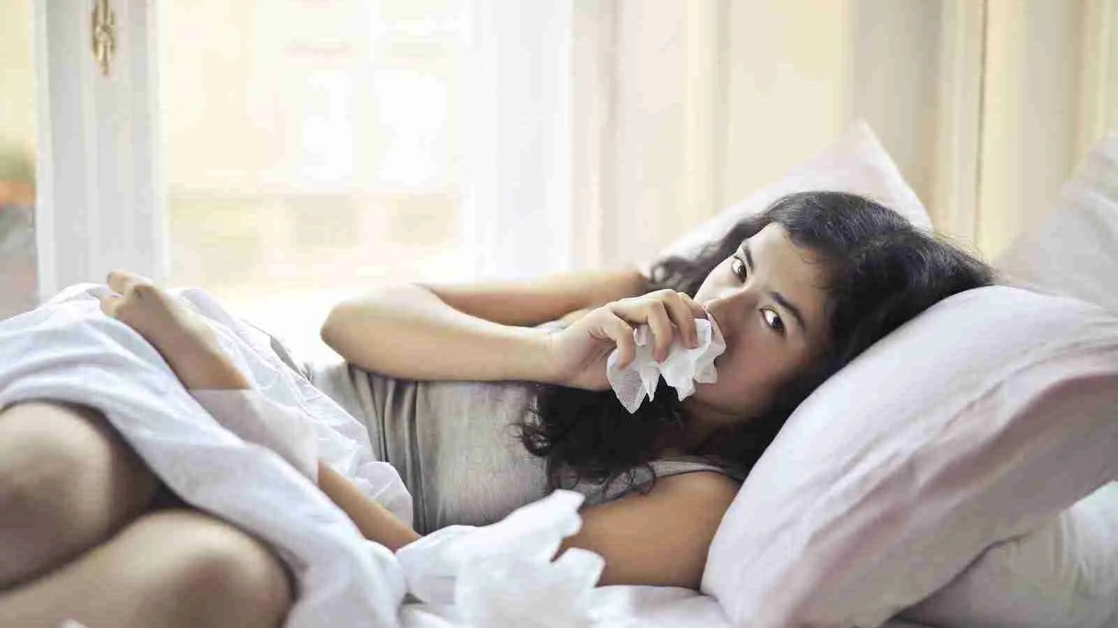 Woman Lying on Bed While Using Tissue