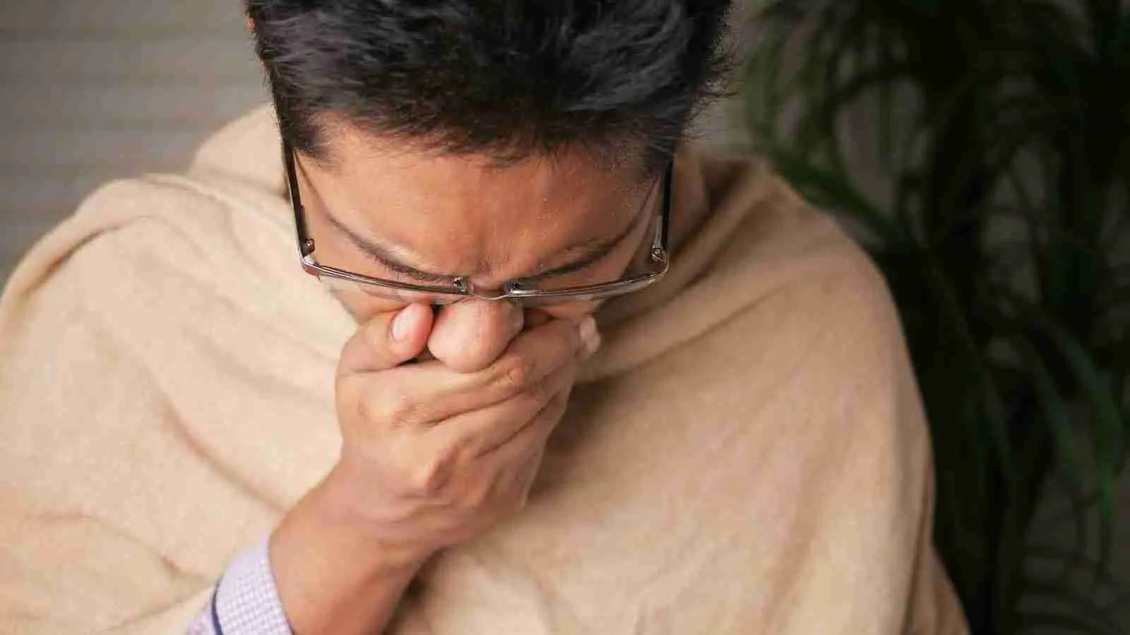 A man covering his mouth as he coughs