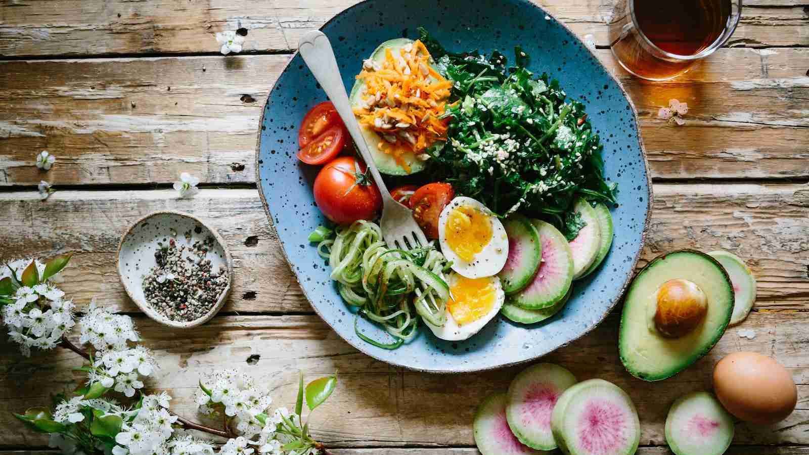 poached egg with vegetables and tomatoes on blue plate