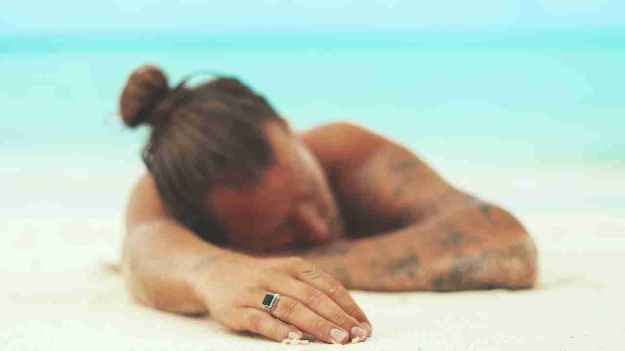man wearing silver-colored ring laying on the beach.