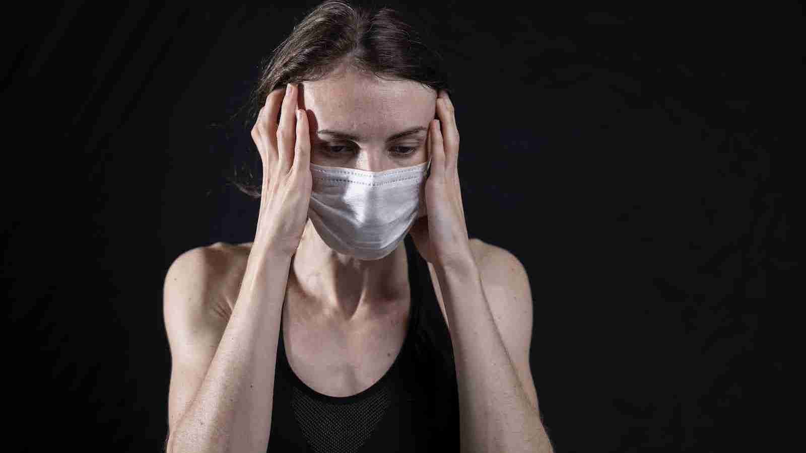 woman in black tank top covering her face with her hands
