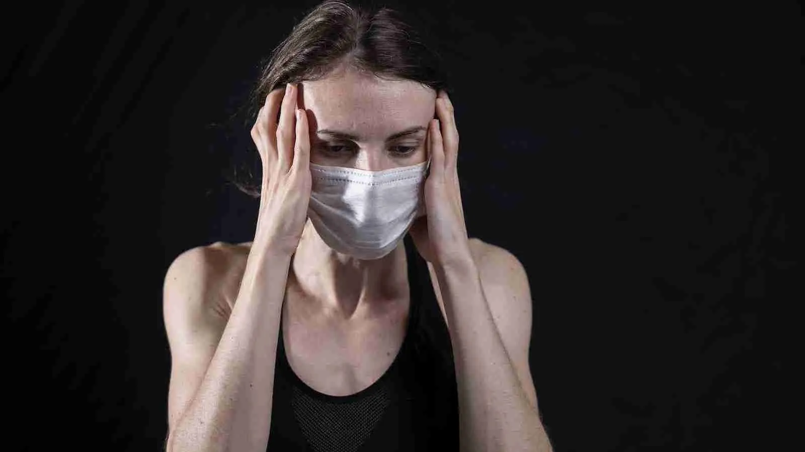 woman in black tank top covering her face with her hands