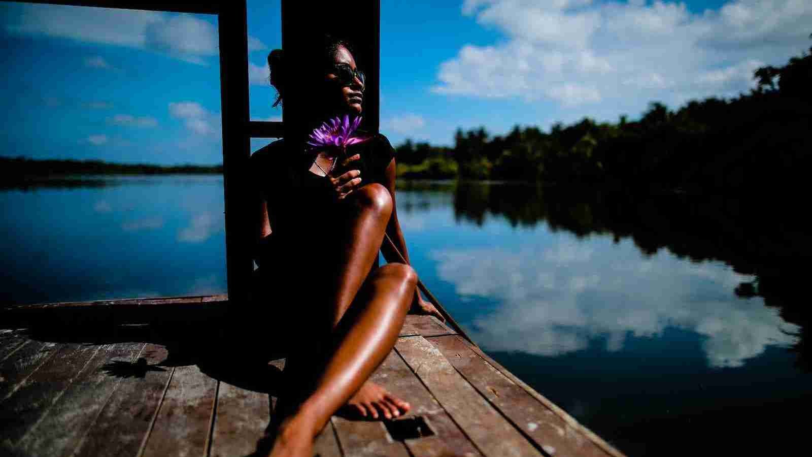 woman sitting near a body of water under sun