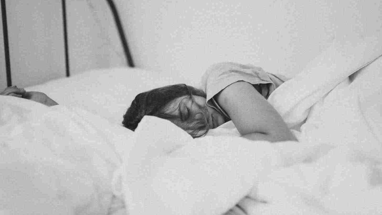 grayscale photo of sleeping woman lying on bed