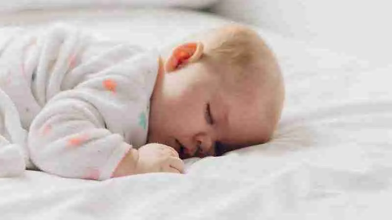 photo of baby laying on bed