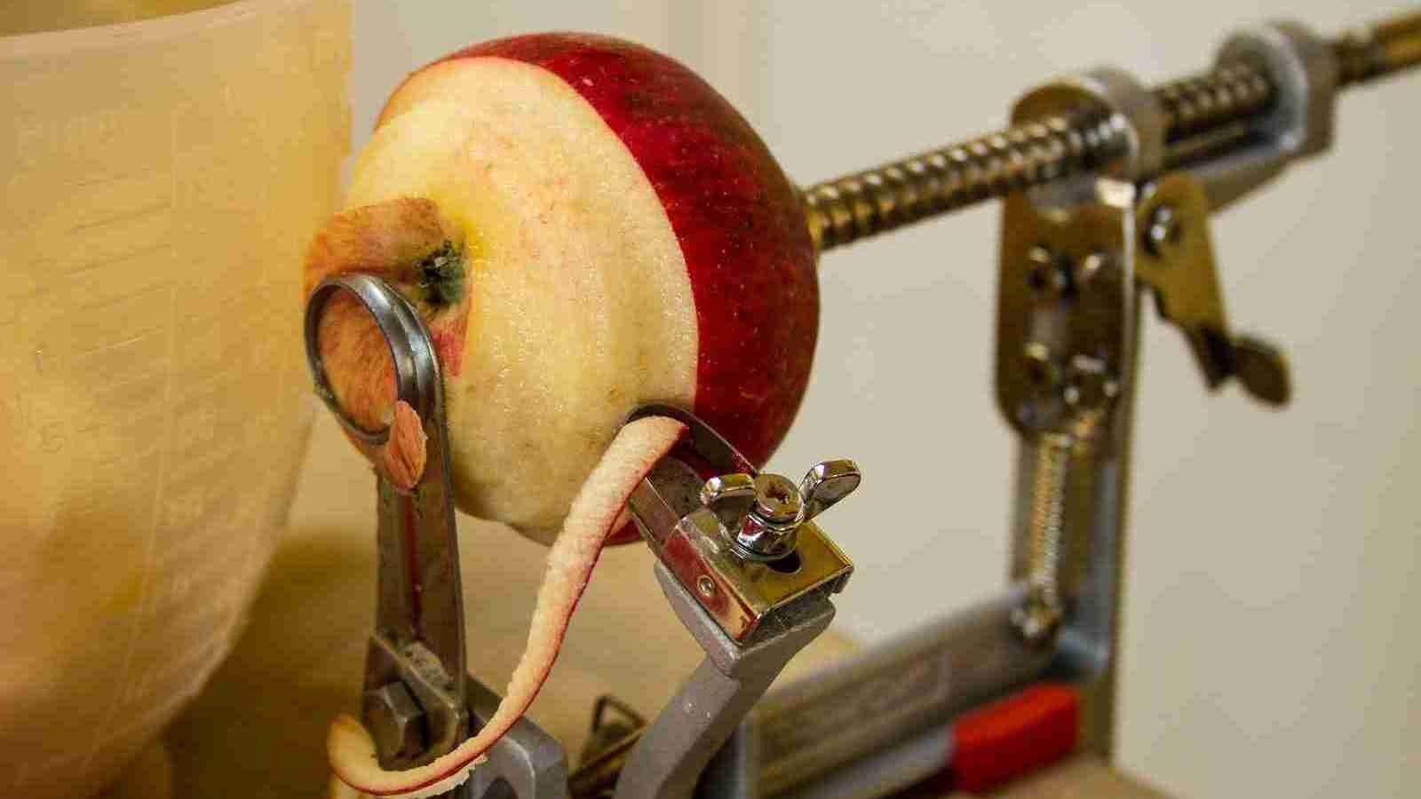 red apple being peeled by a machine
