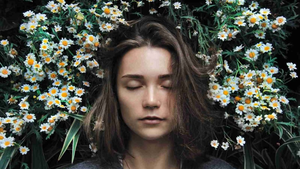 woman closing her eyes on white flower